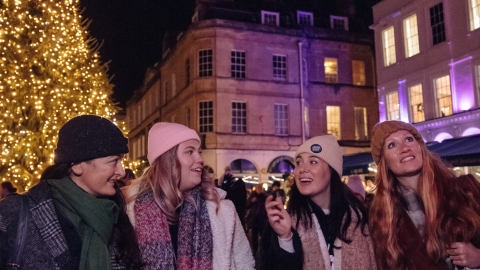 four women standing infront of a christmas tree