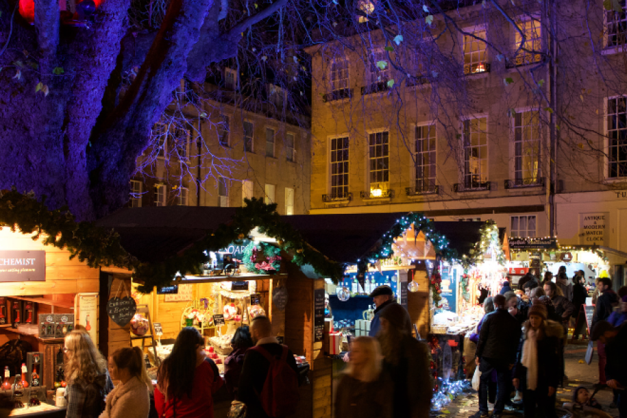 A row of twinkling chalets with Abbey Green tree lit up in hues of red and purple