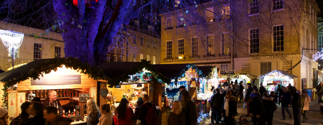 A row of twinkling chalets with Abbey Green tree lit up in hues of red and purple